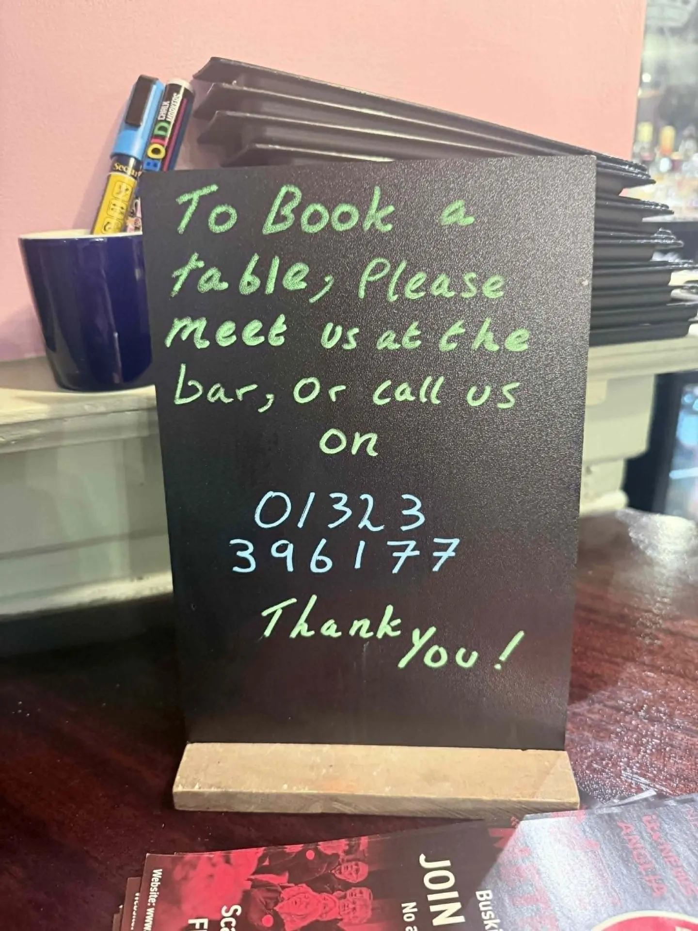 Chalkboard sign at The Alexandra Arms — To book a table, please meet us at the bar, or call us on 01323 396177